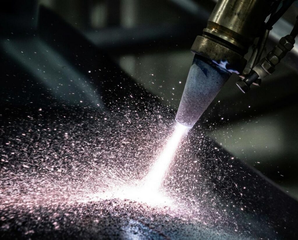 Individual applying a spray finish to a metal object with a specialized machine for coating.